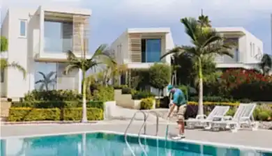 A luxurious villa managed by Leptos Estate, featuring a person maintaining the property.