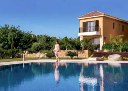 A photo of a woman standing in front of the Venus Garden Villa, with the swimming pool in the background.