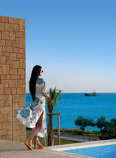 A woman admiring the seaside view from a property situated right by the sea.